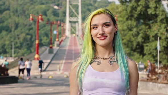 Teenager with Multicolored Yellow Blue Hair Tattoos Piercings and a Tunnel in the Earlobe alt