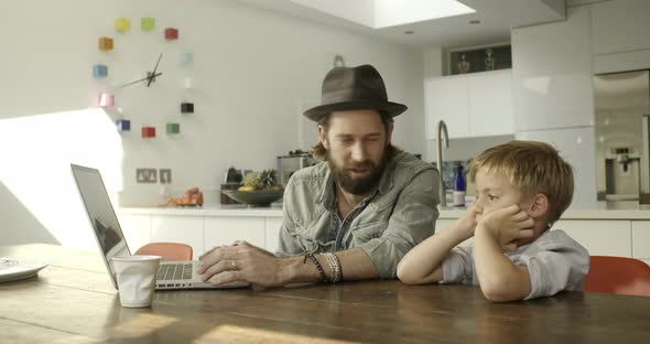 Father and son using laptop in kitchen