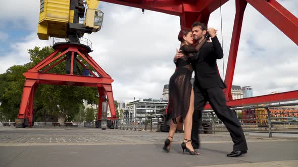 Couple of sexy tango dancers doing a difficult routine under the cranes of Puerto Madero neighborhoo alt
