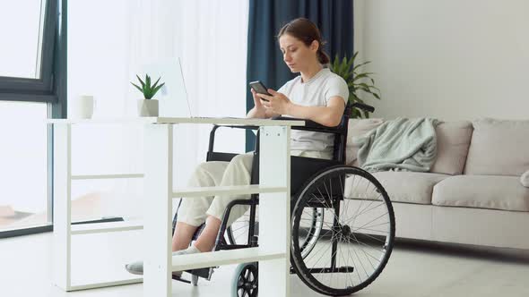 Motivated Freelancer Uses Smartphone Sitting in Wheelchair at Home alt