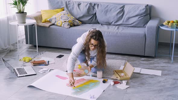 Woman Draws Abstract on Paper on Floor in Room