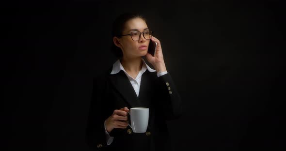Woman is Talking Seriously on the Cell Phone and Holding a White Coffee Mug