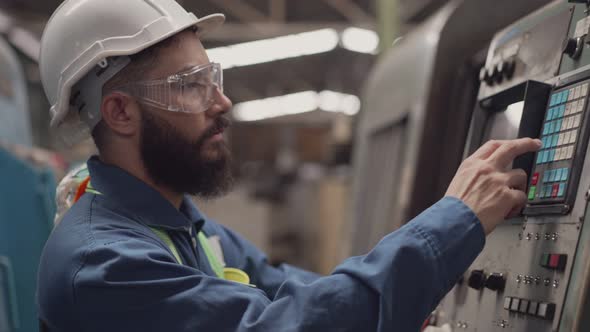 Male engineer worker in safety uniform walking and checking on factory machine alt