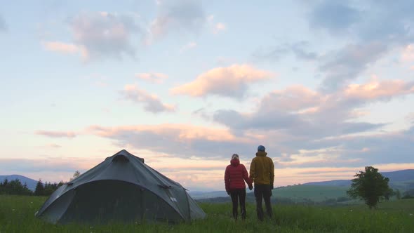 camping couple, two people camping and looking at a surrounding landscape,