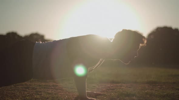 Attractive Young Man Doing Press Ups In The Park During Golden Hour In Slow Motion alt