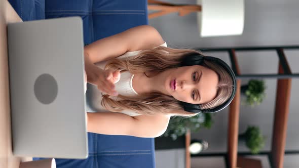 VERTICAL VIDEO POV Blonde Female Wearing Headphones Talking Online Video Call Use Laptop at Home alt