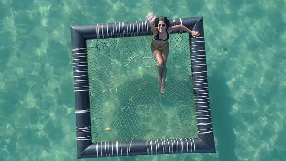 Girl relaxing in an inflatable pool in the ocean, Koh Kood, Thailand DRONE TOP DOWN FLY UP CROPPED alt