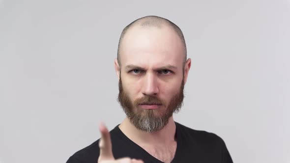 Strict man raising finger in warning gesture over grey background.