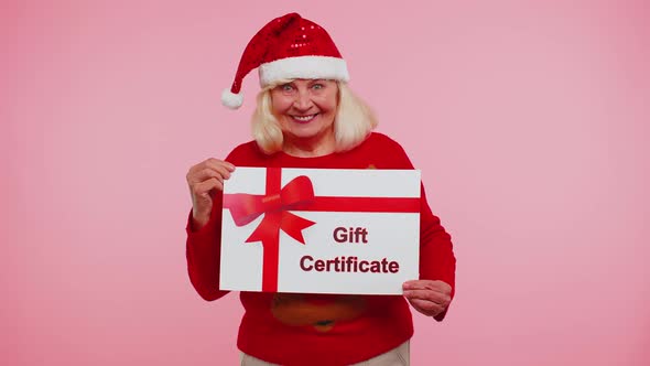 Elderly Grandmother Woman in New Year Sweater Presenting Card Gift Certificate Coupon Winner Voucher alt