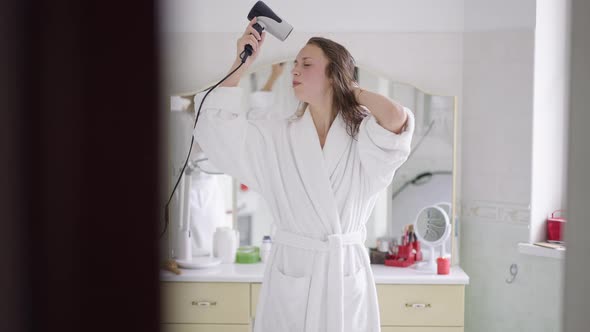 Portrait of Slim Happy Woman Singing Dancing Drying Hair with Hair Dryer in Slow Motion alt