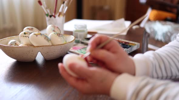 Defocudes of Woman Painting a Water Colors on Fantasy Chicken Eggs for Easter Egg Festival alt
