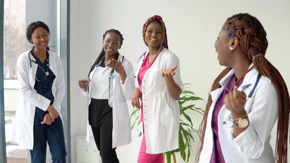 A Young African American Female Doctor Stands in Front and Looks at the Camera Against the alt