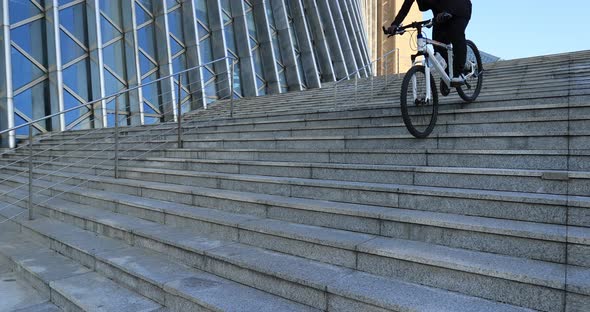 Woman free rider riding bike going down city stairs alt