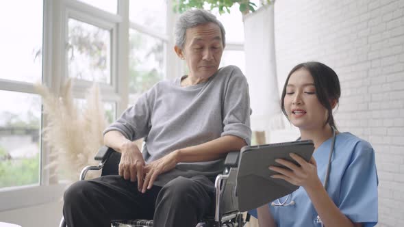 Young Asian nurse diagnose disease by talking to a senior male patient on a wheelchair. alt
