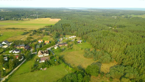 Aerial - flying over private houses surrounded with green leafy forest in Sasino village, Poland on alt