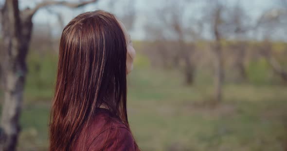 Young Brunette Woman with Long Hair Stands Among the Trees and Meditates alt