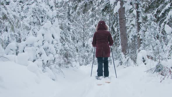 A woman walking through deep snow in forest