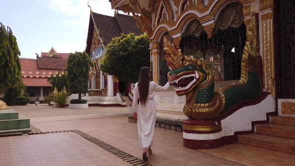 Young woman tourist walking in Buddhist Wat Luang Temple, Pakse, Laos. 4K Slow. Asian exotic culture