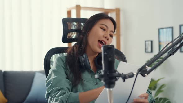 Attractive asia girl record podcast use microphone hold paper creating content for audio blog talk.