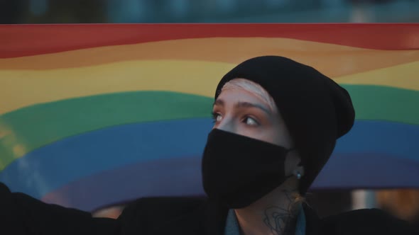 Portrait of Young Woman with Face Mask and Rainbow Flag. Concept of Sexual Orientation Acceptance alt