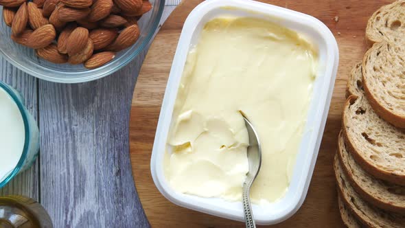 Salted Butter in a Plastic Container and Breads on Table alt