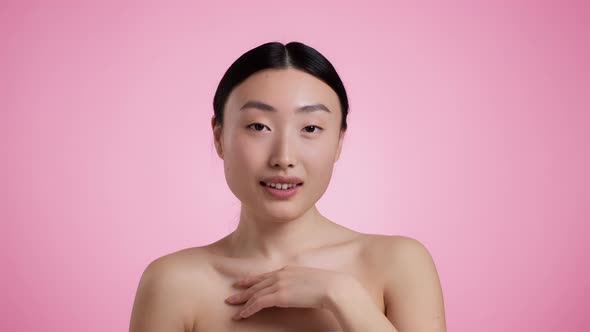 Young Attractive Wellgroomed Asian Woman Touching Her Neckline Enjoying Condition of Her Skin Pink alt