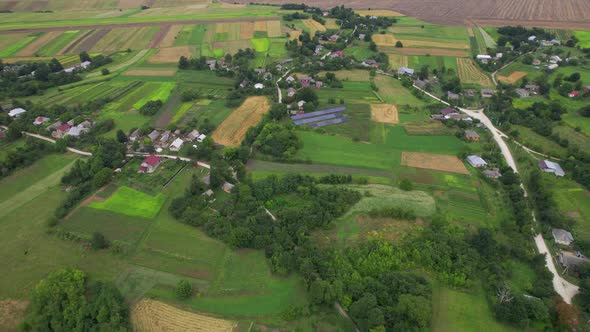 Aerial View From the Flight Over a Typical Old Village with Fields Solar Station and Road in Summer alt