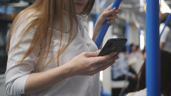 A Woman in a Subway Car Uses a Smartphone