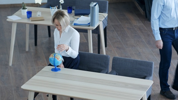 Calm single young woman relaxing at work looking at globe