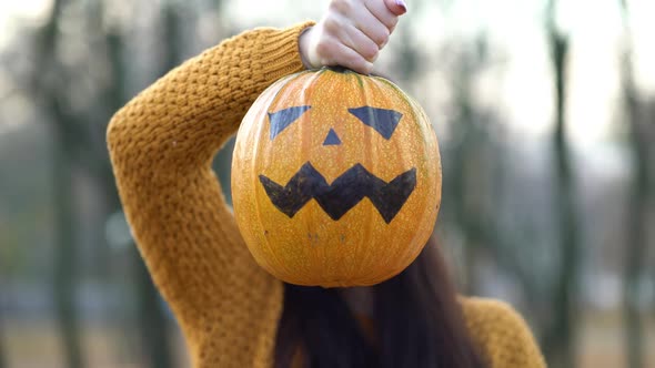 Woman Holding Jack-o-lantern Pumpkin in Autumn Park