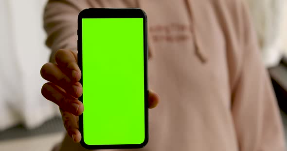 Woman Shows Smartphone with Green Screen alt