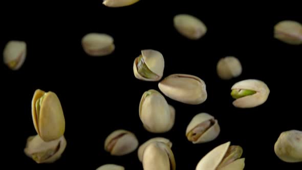 Closeup of Salted Pistachios Flying Up on a Black Background alt