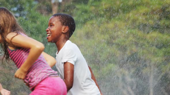 Kids playing with garden sprinkler alt