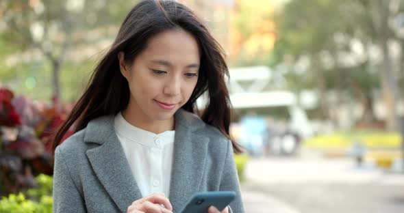 Asian Business woman look at smart phone in city alt