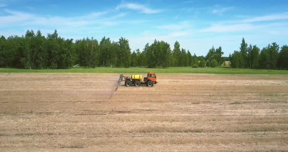 Tractor Trailer for Spraying Fertilizers Moves on Harvested Field alt