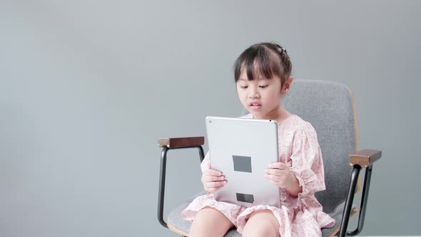 Child watching digital tablet and looking at cheerful camera. alt