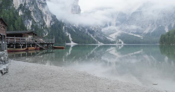 POV Walking to Boathouse with Wood Pier and Boats on Braies Lake in Cloudy Day alt
