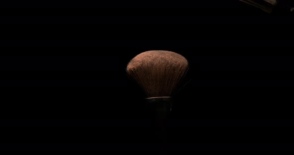 Make-up Brush spreading blush powder on black background, Slow motion 4K alt