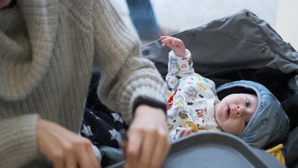 baby lies next to mom on jackets while mom eats in a cafe