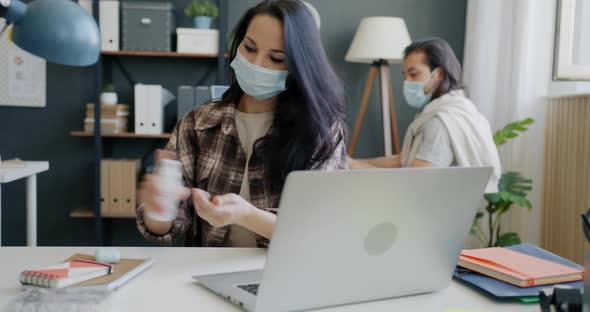 Young Woman Coming to Workplace Washing Hands with Sanitizing Gel Then Working with Laptop alt
