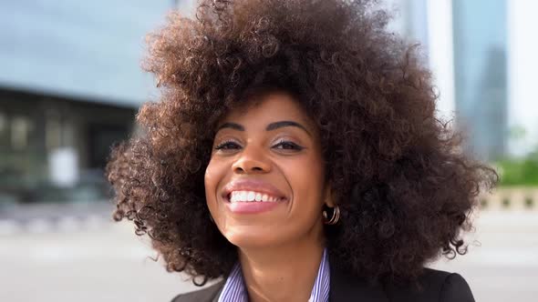 Happy african business woman smiling on camera with city in the background