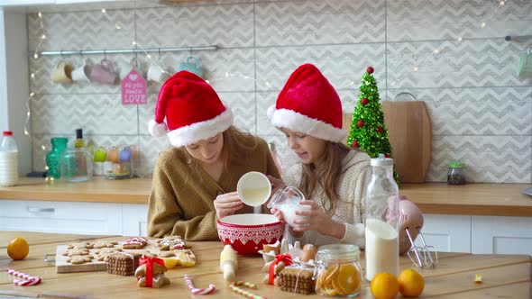 Little Girls Making Christmas Gingerbread House at Fireplace in Decorated Living Room