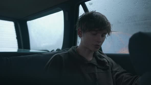 Hipsterlooking Young Man Sits in a Car in the Rain and Gives an Interview Into the Lavalier alt