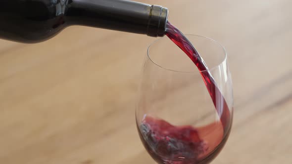 Red wine is poured from bottle into glass alt