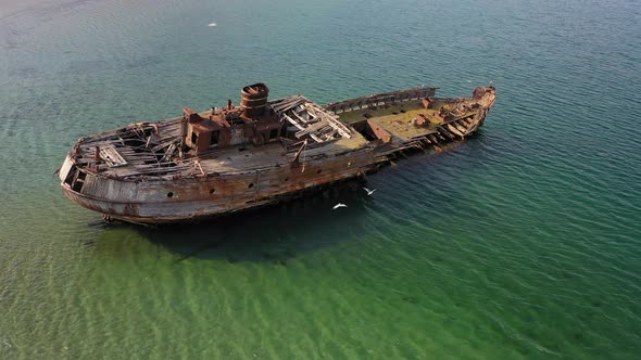A Wrecked Wooden Ship Lies on the Seashore Covered with Rust alt