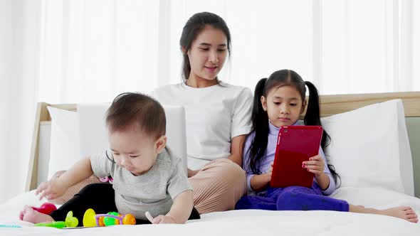 Busy mother with two daughters multitasking with laptop, Super mom concept