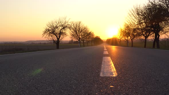 A Deserted Highway Leads Toward the Golden Sunset in a Rural Area  View From the Middle of the Road alt