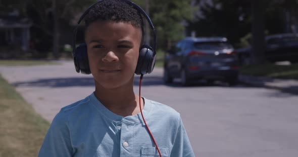 Young African american kid close up listening to music outdoors on headphones alt