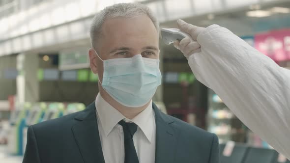 Close-up Portrait of Mid-adult Businessman in Face Mask Standing in Airport Departure Area As alt