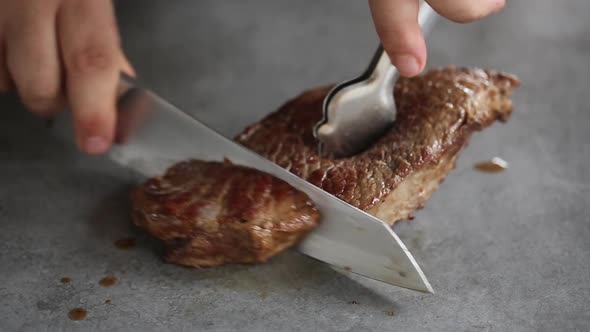 Chef cutting prepared beef steaks with knife